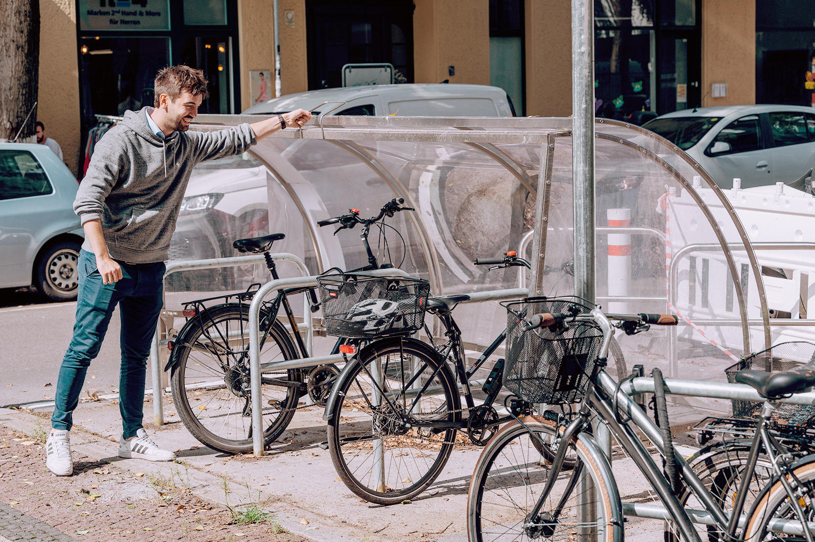 Eine Person steht links neben der Fahrradgarage und öffnet die Fahrradgarage.