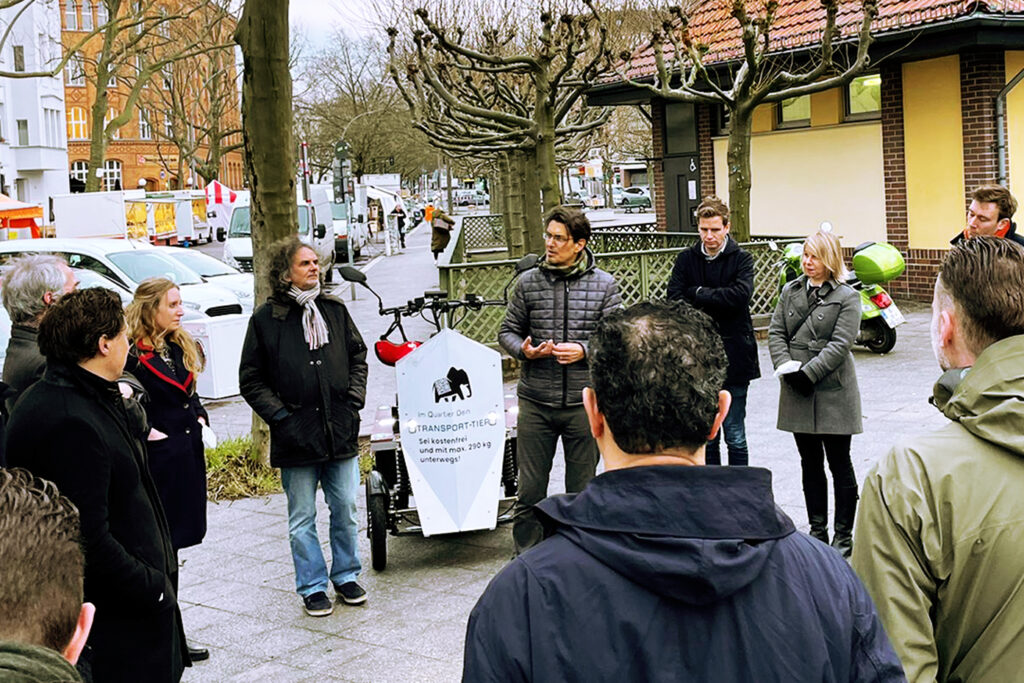 Rolf Mienkus, Oliver Schruofeneger und Besucher aus Amsterdam stehen gemeinsam am Mierendorffplatz